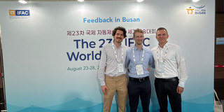 Das Bild zeigt drei Personen, die vor einem Banner der IFAC-Konferenz 2026 in Busan stehen.