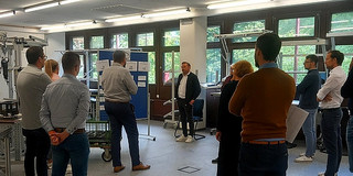 Die Workshopteilnehmer stehen im Halbkreis vor einer Aufstellwand.