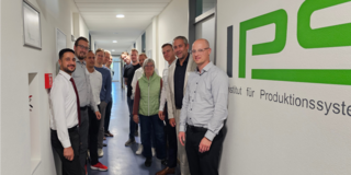 Gruppenbild mit den Teilnehmenden der ersten Sitzung des Projektbegleitenden Ausschusses neben dem IPS-Logo	
