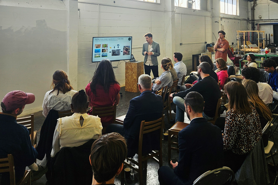Vortrag mit Zuhörenden in einer Lagerhalle