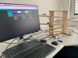 Im Vordergung: Computerbildschirm, Tastatur und Maus. Im Hintergrund: Holzmurmelbahn.
