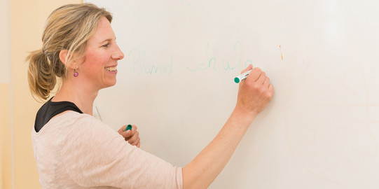 Eine Frau schreibt mit einem Stift an ein Whiteboard.